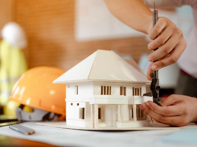 close-up-of-male-architect-hands-measuring-and-making-model-house-on-the-desk-at-sunset-.jpg close-up-of-male-architect-hands-measuring-and-making-model-house-on-the-desk-at-sunset-.jpg